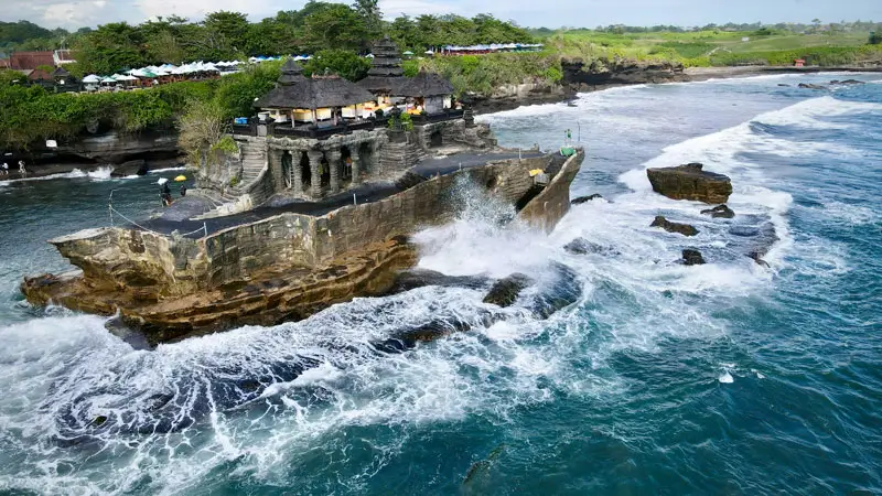 Pura Tanah Lot di atas batu karang dengan ombak menghantam saat pasang