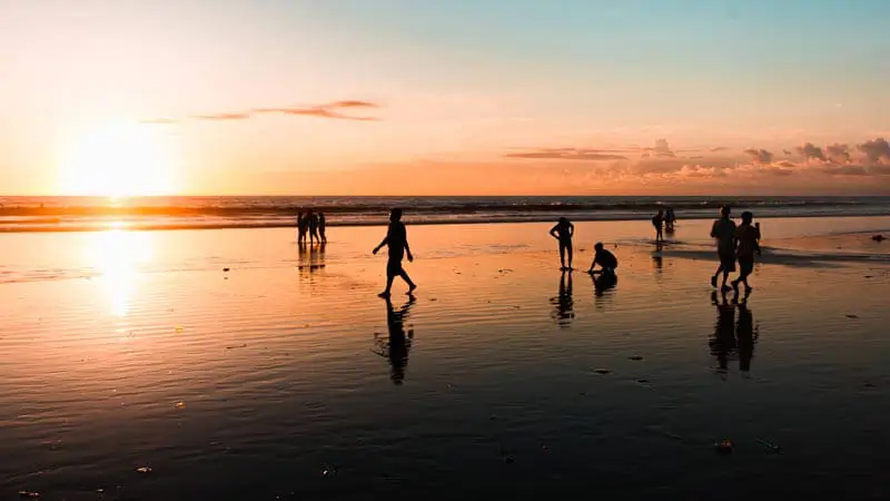 Sunset di pantai kuta bali dengan wisatawan menikmati pantai