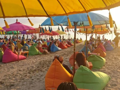 Payung warna-warni dan suasana santai di Pantai Seminyak saat sunset.